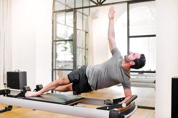 Fit man doing pilates side elbow plank exercises - obrazy, fototapety, plakaty