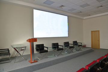 Leather chairs, glass tables and a tribune for speeches on the stage in the hall for presentations