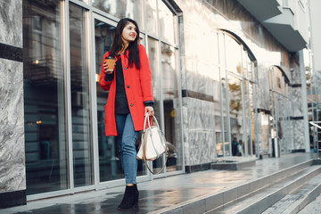 Beautiful girl in a city. Stylish girl in a fashionable clothes. Lady standing near gray building.