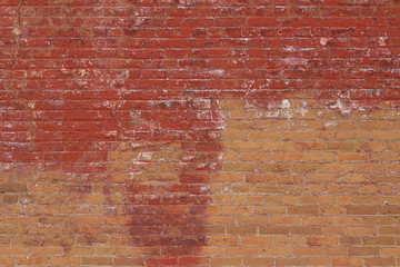 Vintage weathered clay brick wall texture background with blotchy deteriorating red paint