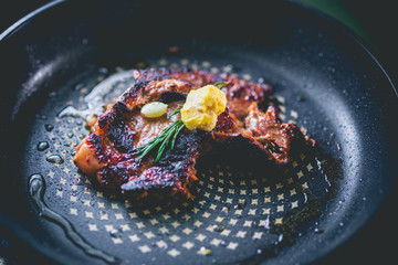 Cooked beef steak with rosemary and garlic inside iron skillet