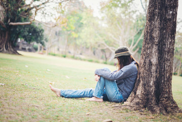 Sad woman sit down in field with sunlight background.