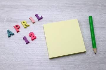 April 12 - Daily colorful Calendar with Block Notes and Pencil on wood table background, empty space for your text or design