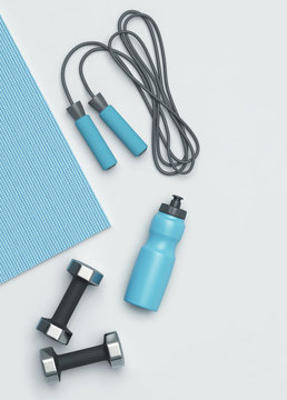 Fitness mat, dumbbells, jumping rope and a bottle of water on the floor