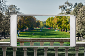 Fototapeta premium Autumn park with relaxing people on the grass, saturated image in smartphone s camera