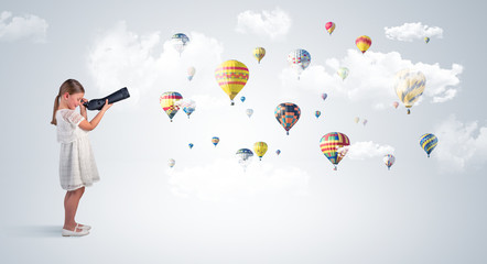Cute girl looking to air balloons through a telescope