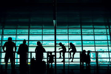 Travel with Kids Concept. Silhouette of a Big Family Passengers Waiting for Boarding in Departure Terminal in the Airport