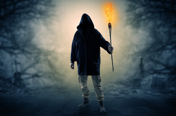 Man with burning flambeau coming from thicket and looking something