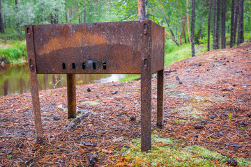 Tourist barbecue for shish kebab in the background of the taiga river in forest.