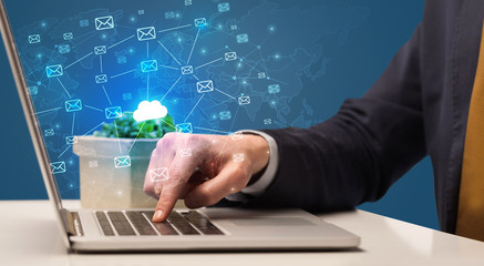 Businessman hand sending a bunch of messages on laptop with cloud computing concept