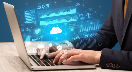 Businessman hand typing on laptop with reports and graphs concept around