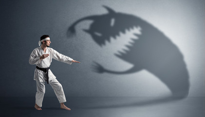 Young karate man fighting with a big black scary shadow