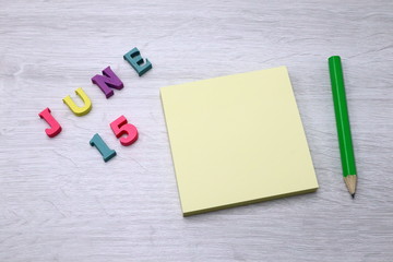 June 15 - Daily colorful Calendar with Block Notes and Pencil on wood table background, empty space for your text or design