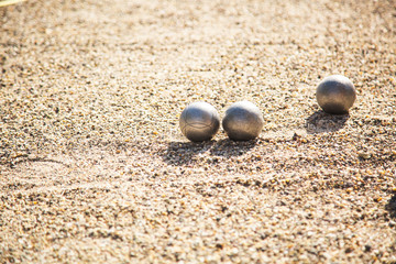 Silver Petanque or Bocce balls on gravel ground with a blur background
