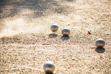 Silver Petanque or Bocce balls on gravel ground with a blur background