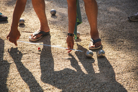 Senior person checking the distance between a boules and the jack for the result