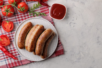 Delicious grilled sausages on a plate with red sauce and spices on a light background. B-B-Q. top view