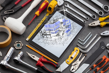 Tablet with construction tools and 3d house plan concept