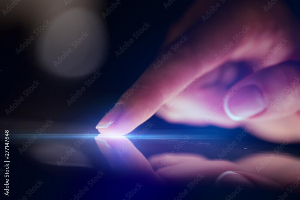 Poster finger touching tablet with dark background with copyspace