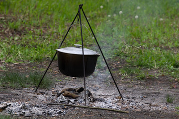 Cooking in field conditions, boiling pot at the campfire on picnic