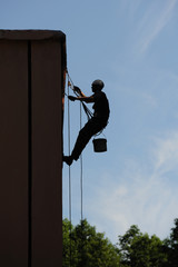Industrial alpinism. The man is repairing the facade of the building.