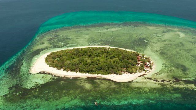 Tropical island and sandy beach surrounded by atoll coral reef and blue sea, aerial view. Small island with sandy beach. Summer and travel vacation concept, Mantigue Philippines Mindanao