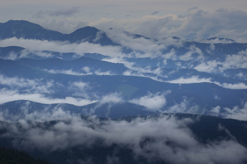 Fototapeta na wymiar Mountain range with visible silhouettes through the morning colorful fog.