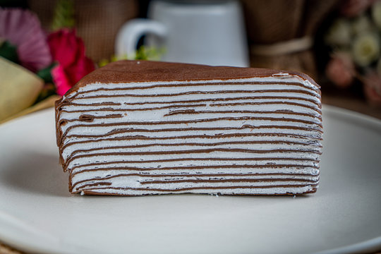 Piece of Chocolate crepe cake on white ceramic plate