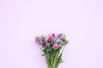 Bouquet of wild flowers on a light pink background close-up. Gentle romantic background, pink and white clover.