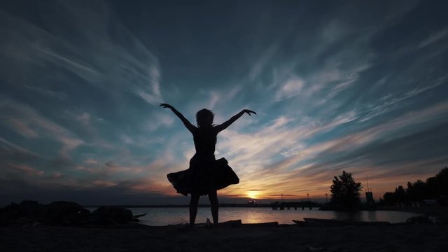 girl in a flying dress whirls and dances. silhouette of a young girl at sunset.