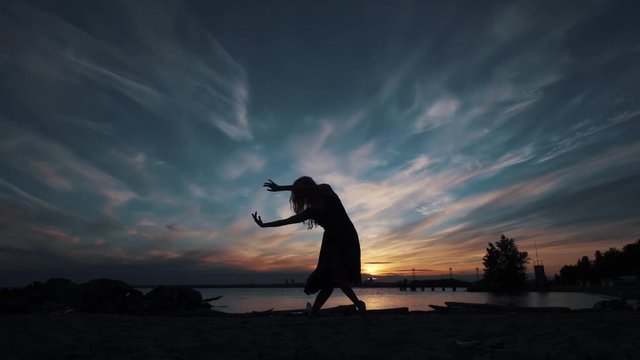 silhouette of a girl dancing on the background of the sunset sky.