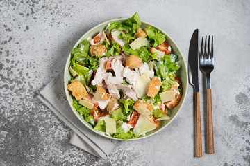 Caesar salad with chicken, Parmesan and wheat croutons on a vintage grey background. Light diet dinner.