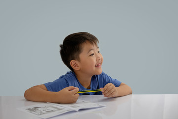 Asian boys are doing some writing on the book.