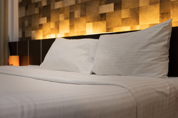 Hotel room service hands set up white pillow on the bed in the hotel