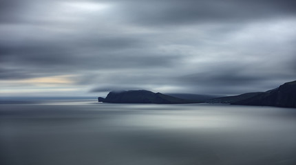 Fototapeta premium Sorvagsvatn lake cliffs backlit long exposure in the horizon at sunset, Faroe Islands