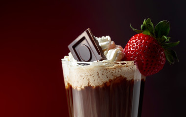 Chocolate drink with whipped cream, strawberry and pieces of black chocolate.