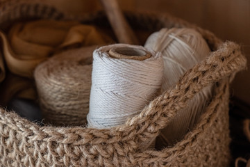 Macrame, cotton and hemp ropes in skeins. Crocheting, netting handicraft objects in a basket made...