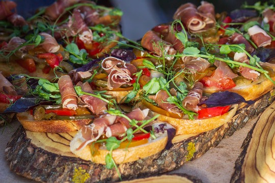Close up bruschetta with proschuto, tomato, parmesan cheese and arugula