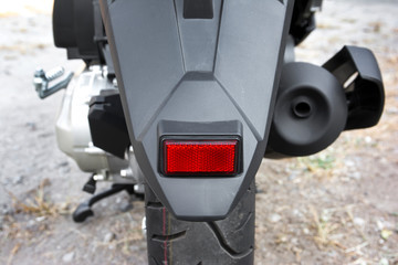 Motorcycle rear fender with reflector background. Motorcycle back fender with red reflector