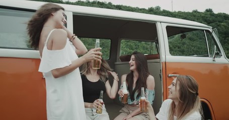 Closeup middle of nature orange vintage van beautiful ladies drinking beer and happy cheers with each other