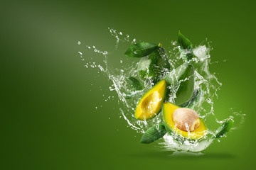 Water splashing on Fresh Sliced Green avocado over the Green background.