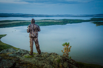traveler hunter looks at mountain lake twilight landscape