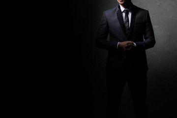 Obraz na płótnie Canvas Young handsome successful business man in a suit. Isolated on dark background, copy space.