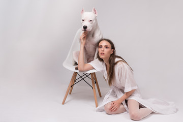 Beautiful fashionable young woman in white dress sitting on the floor  and touching her lovely...