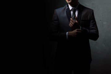 Young handsome successful and confident bearded business man in a suit. Isolated on dark background, copy space.