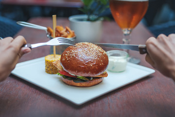 hands holding a burger on the background of the table table in a cafe, fast food concept