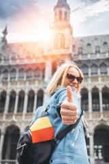 Fototapeta premium A female traveler stands on Grand Place Square in Brussels and shows her thumbs up, Belgium.