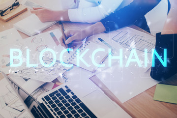 Cryptocurrency hologram over woman's hands writing background. Concept of blockchain. Multi exposure
