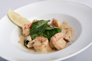 Salad with shrimp. Appetizing prawns with cream sauce close-up on a white plate