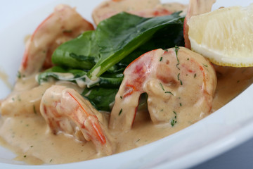 Salad with shrimp. Appetizing prawns with cream sauce close-up on a white plate